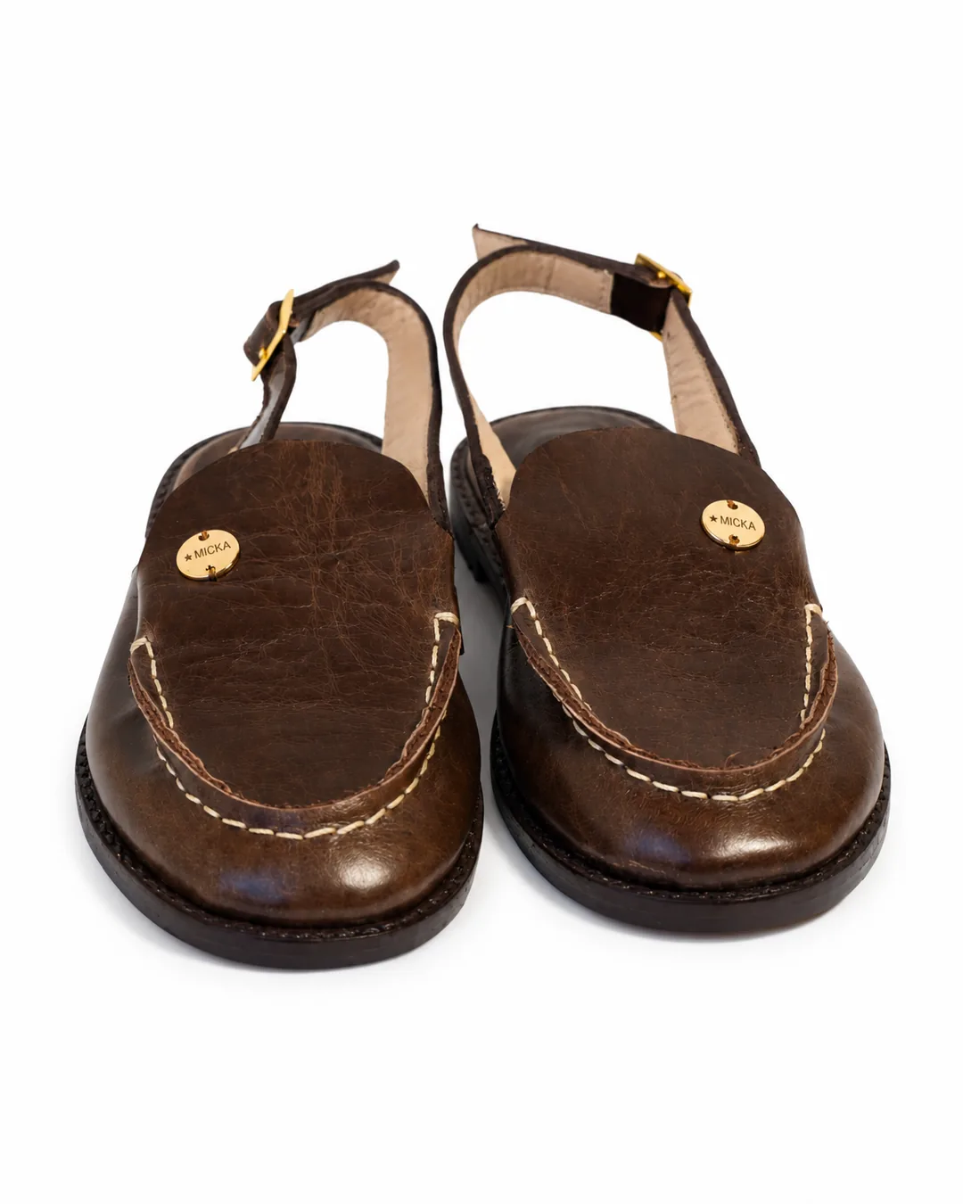 Par de mules slingback en cuero café con las placas Micka a la vista